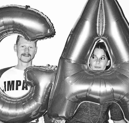 Two people holding balloon letters G and A